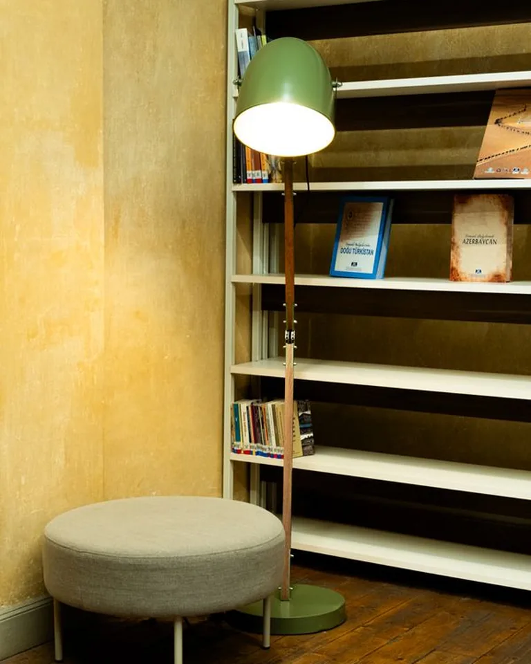 A cozy reading corner with a modern floor lamp beside a bookshelf