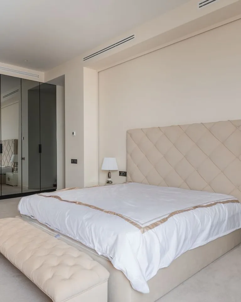 Upholstered storage ottoman bench at the foot of a bed in a small bedroom