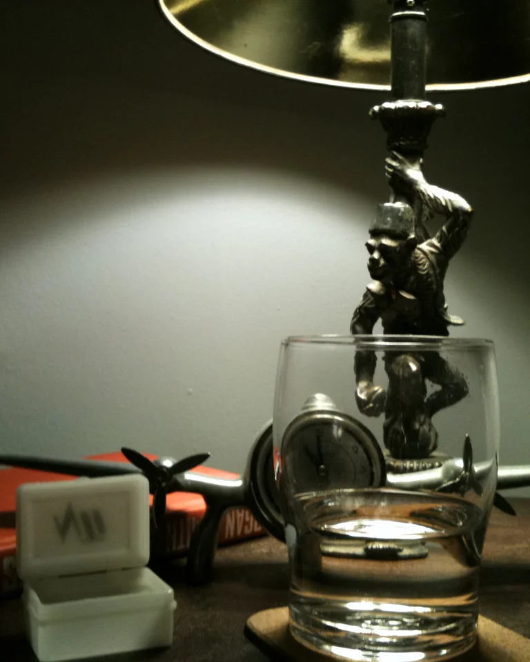 A styled nightstand top with a lamp, a glass of water, and a book under warm light