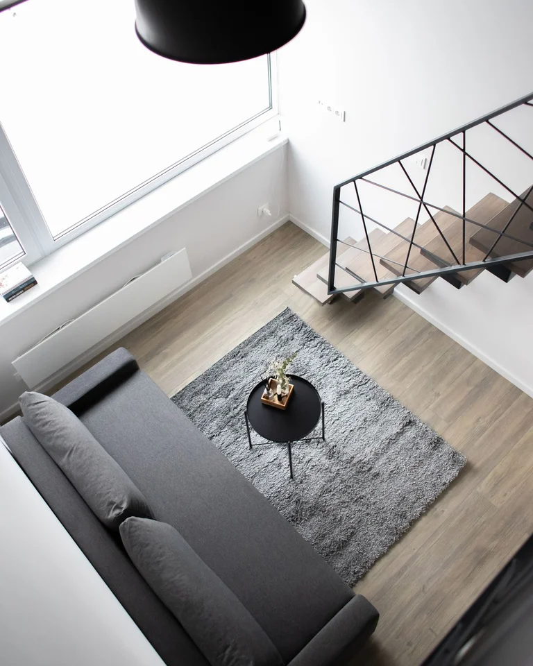 A low sofa and rug in an open living area beside a large window