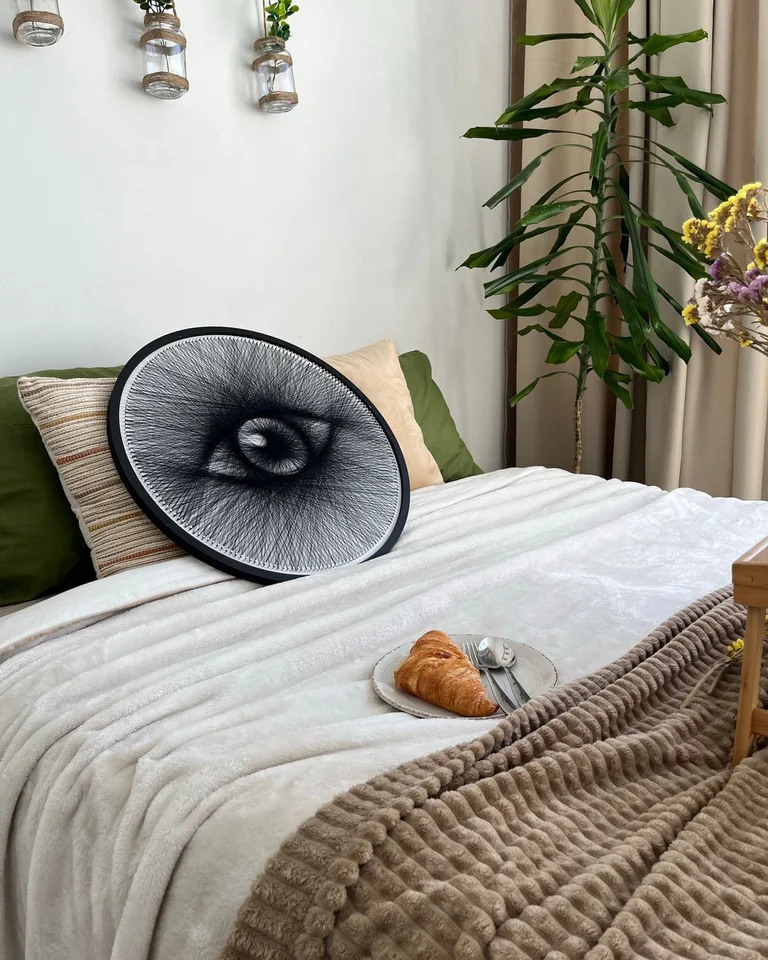 Close view of layered bedding with linen sheets, a chunky knit throw, and soft cushions in a studio bedroom