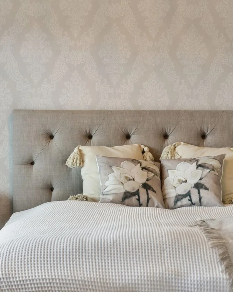 A neatly made bed with a tufted headboard and a clear bedside table