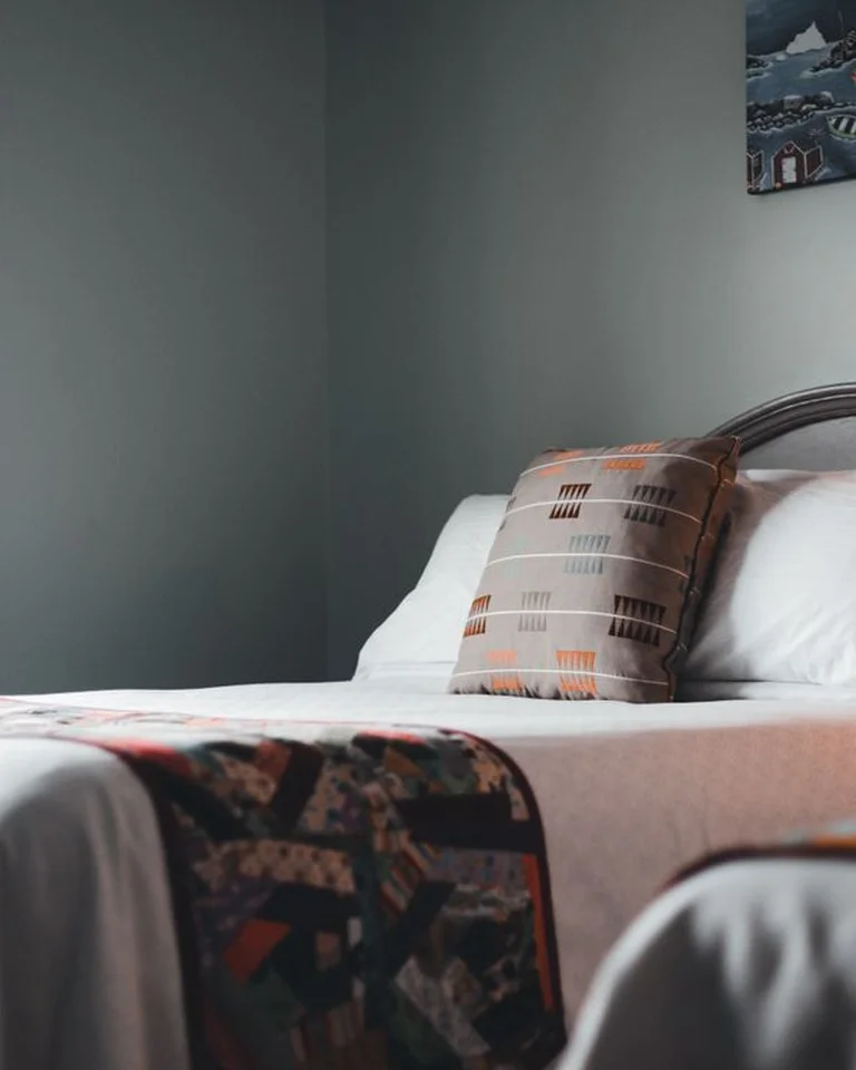 A neatly made bed in a tidy, minimal small bedroom