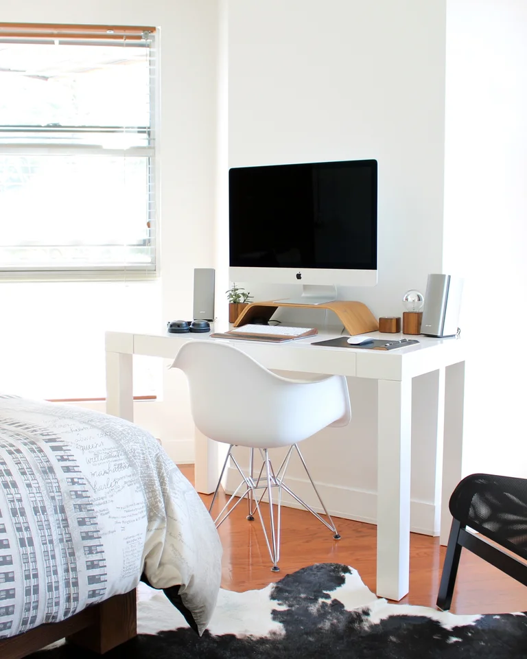 A bright loft bedroom with a bed and a desk sharing one open room