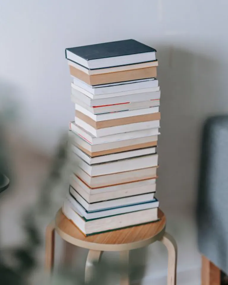 Stack of books used as a riser for a small vase on a dresser