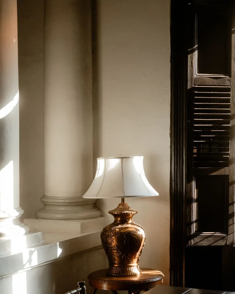Brass table lamp with a white shade glowing in warm light
