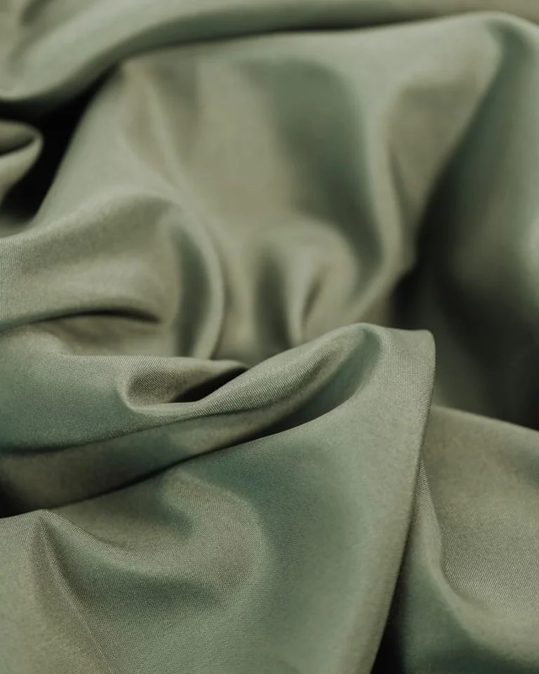 Close-up of soft sage green fabric in layered folds