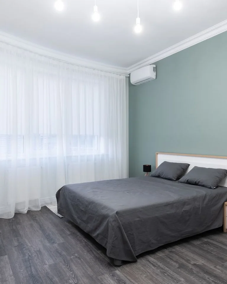 Bedroom with sage green accent wall behind the headboard and white side walls