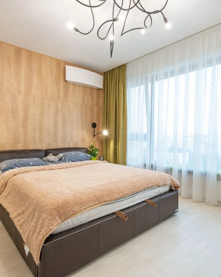 Bright bedroom with green curtains and sheer panels framing a large window
