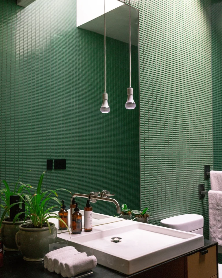 Overview of a small bathroom combining green walls, white tile, and wood accents