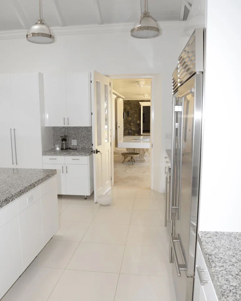 Bright white kitchen with stainless steel appliances and pendant lights above clean countertops