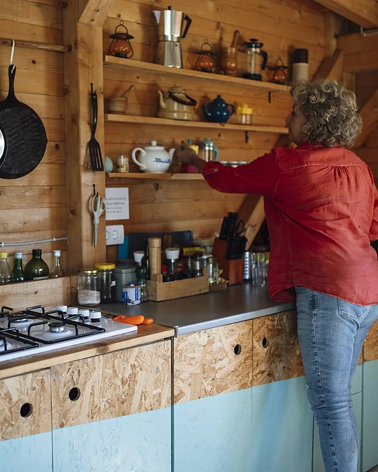 Person arranging dishes on warm wooden open kitchen shelves
