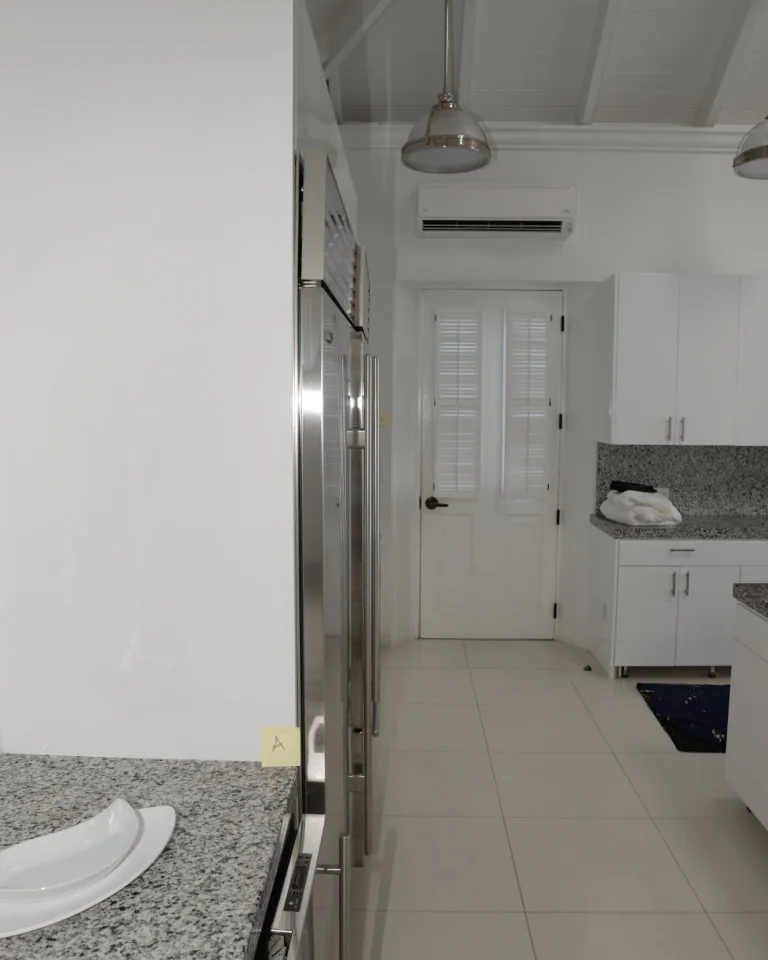Modern white kitchen with pendant lights over granite countertops