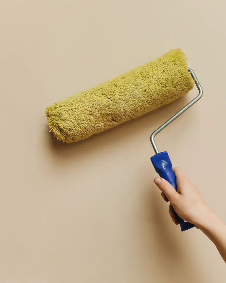 Hand using a paint roller to paint a wall during a DIY project