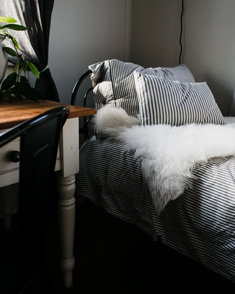 Bedroom with striped bedding and soft fur accents