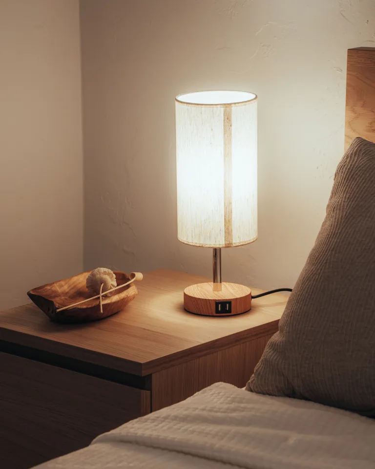Glowing lamp on a wooden nightstand in a warm bedroom