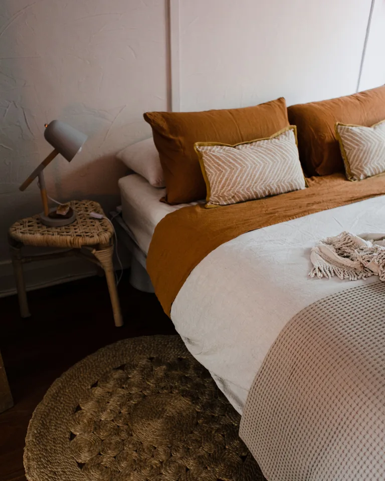 Cozy bedroom in earthy tones with a woven rug and bedside lamp