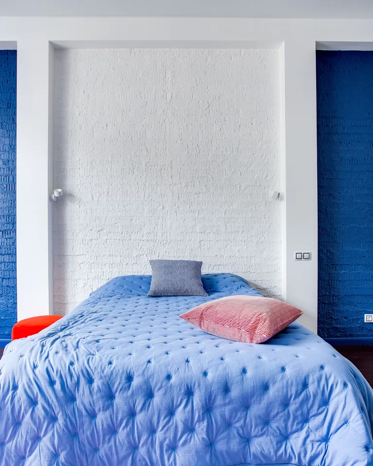 Modern bedroom with navy blue walls, cozy bed and stylish pillows
