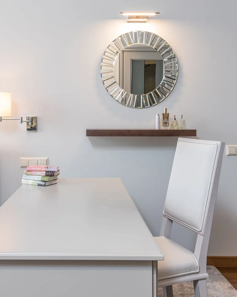 Stylish mirror mounted on a light bedroom wall