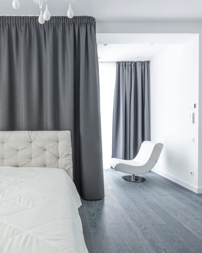 White bedding with soft gray curtains in a minimalist bedroom