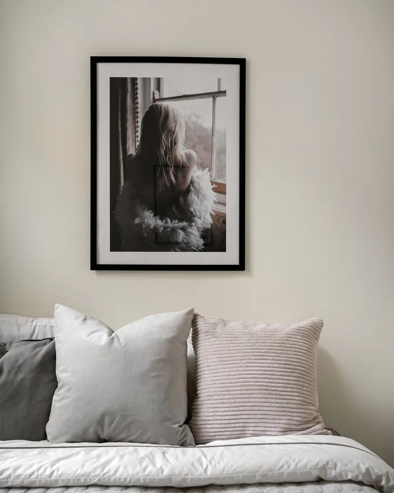 Framed photograph hanging above a plush bed with pillows