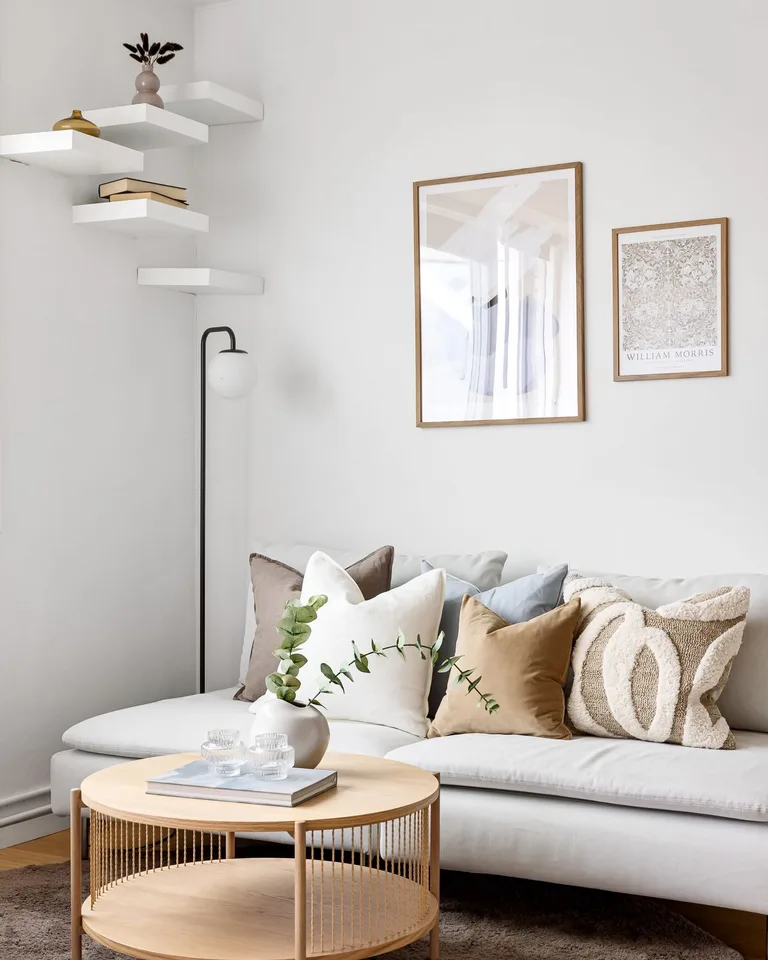 Framed neutral prints hanging above a white living room sofa