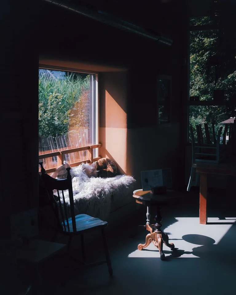 Sunlit window-seat reading nook with a sheepskin throw and small table