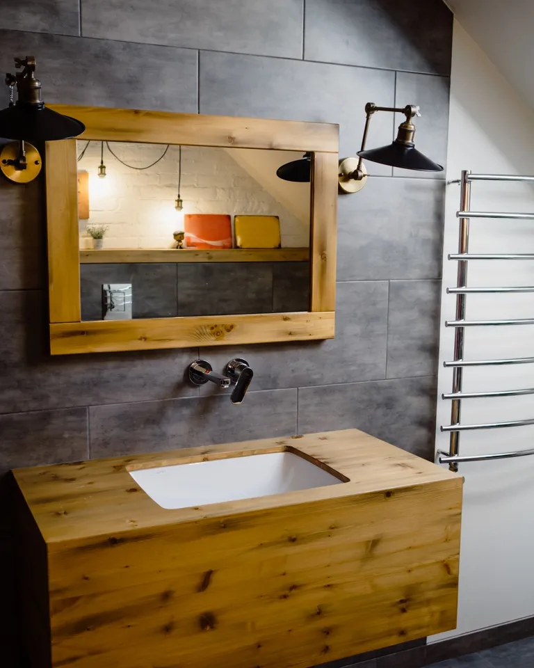 Warm glowing wall sconces flanking a wooden-framed bathroom mirror