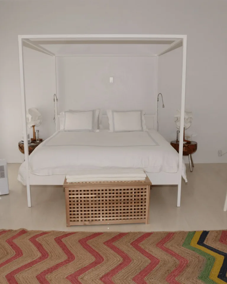 White four-poster bed with a woven storage bench at its foot