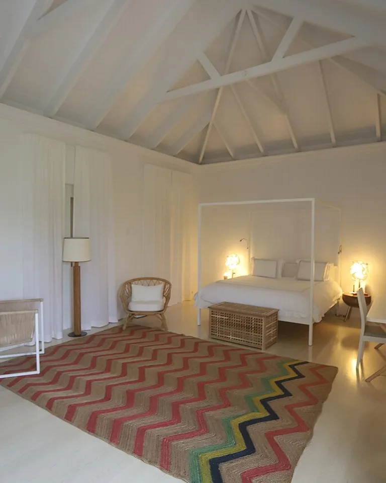 Bright all-white bedroom with vaulted ceiling and four-poster bed